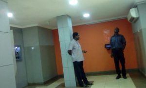 a confused security man listening to an aggrieved GTBank customerinside the E Branch on Ring Road
