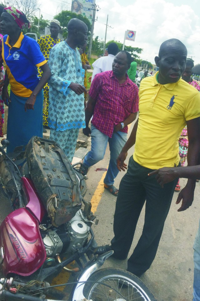 ...'Mr Niyi', right, the lucky private motorcycle rider who jumped off the way...his motorcycle is seen here after being crushed...