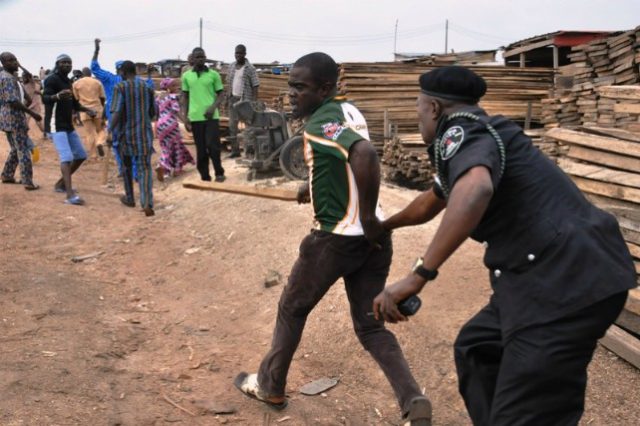 ...a police officer here 'deals' with a plank market protester in Ibadan...