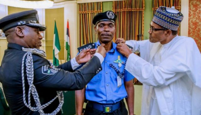 Mr Abubakar Mohammed Adamu, the new Acting IGP being decorated by President Muhammadu Buhari, right...