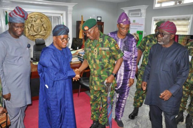 The GOC, Major General Okwudili Fidelis Azinta in a handshake with Osun State Governor, Alhaji Isiaka Adegboyega Oyetola in the governor's office, Osogbo while others look on…