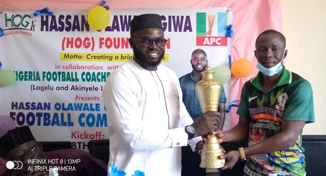 Hassan Giwa Football …presenting the trophy to the General Secretary, NFCA, Coach Akinwumi Isogun…