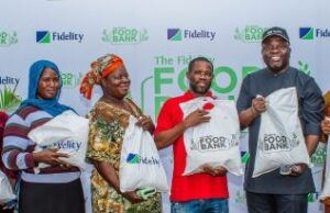 Eti-Osa Community Joins Others To Enjoy Fidelity Bank’s Food Bank Largesse …Henry Asiegbu, Divisional Head, Operations, Fidelity Bank Plc (Left); Adebayo Adeyinka, Executive Technical Assistant to the Managing Director/Chief Executive Officer, Fidelity Bank Plc (5th from Left); Meksley Nwagboh, Divisional Head, Brand and Communications, Fidelity Bank Plc (Right); flanked by some of the beneficiaries at the Fidelity Food Bank outreach in Eti Osa Local Government Area, Lagos recently…