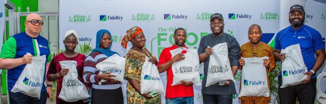 Fidelity Image …Henry Asiegbu, Divisional Head, Operations, Fidelity Bank Plc (Left); Adebayo Adeyinka, Executive Technical Assistant to the Managing Director/Chief Executive Officer, Fidelity Bank Plc (5th from Left); Meksley Nwagboh, Divisional Head, Brand and Communications, Fidelity Bank Plc (Right); flanked by some of the beneficiaries at the Fidelity Food Bank outreach in Eti Osa Local Government Area, Lagos recently…