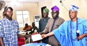 Students In Ijebu Igbo Benefit From Dangote Granite Mines’ Bursary Awards L-R: Shoneye Damilola, a student beneficiary from Beje High school, receiving the bursary Cheque; General Manager, Community Relations, Dangote Granite Mines Ltd, Pastor Joseph Alabi; Dangote Granite Mines Ltd, General Manager, Projects Control, Samuel K. Fagbile and High Chief Ademola Ogunyale, a representatives of His Royal Highness…