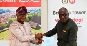 Makinde’s Govt Reveals Plans To Redevelop Historic Bower’s Tower Two men shake hands while exchanging a blue document at a corporate event, with Bower's Tower banners in the background.