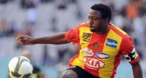 Ex-Super Eagles Striker Slumps, Dies During Training In Kaduna Soccer player in a red and yellow jersey kicking a ball during a match, with blurred stadium stands in the background.