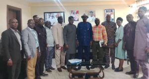 Oyo Govt, FERMA Strengthen Collaboration On Road Maintenance Group of professionals posing for a photo in a conference room, some holding folders, a glass coffee table in front.