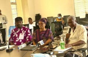 LASSA FEVER: Oyo Govt Confirms 5 Cases, Records 1 Death Diverse group of adults seated around a conference table in a bright room; a man speaks into a microphone while others listen, with notebooks, water bottles, and hand sanitizer on the table.