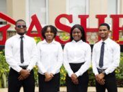 At A4S 2026, Dangote Cement Powers Global Sustainability Innovation Four professionally dressed staff (two men, two women) stand in front of a red 'SALE' sign outside a store.