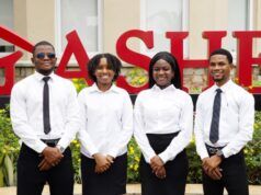 At A4S 2026, Dangote Cement Powers Global Sustainability Innovation Four professionally dressed staff (two men, two women) stand in front of a red 'SALE' sign outside a store.