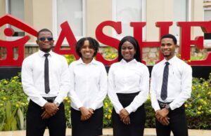 At A4S 2026, Dangote Cement Powers Global Sustainability Innovation Four professionally dressed staff (two men, two women) stand in front of a red 'SALE' sign outside a store.