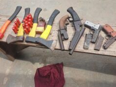 Oyo Police Foil Cult Attack At Ibadan Poly Assorted hand tools laid out on a wooden workbench, including axes, hammers, pliers, and wrenches, with a red cloth on the ground nearby.