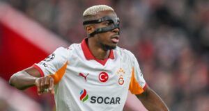 Galatasaray’s Victory Over Fenerbahçe Thrills Osimhen Soccer player in a white Galatasaray jersey with SOCAR sponsor, wearing a protective face mask during a match.