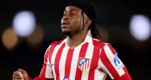 How Lookman’s UCL Dream Was Terminated By Arsenal Soccer player in a red-and-white striped Atlético Madrid jersey runs on the field during a match.
