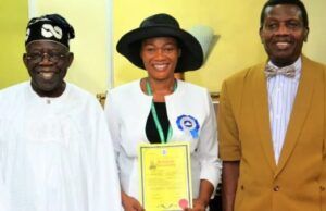 We’ll Not Remove Tinubu’s Wife As Pastor In RCCG – Adeboye Three people pose indoors: a smiling man in white traditional attire, a woman in a white jacket and black hat holding a yellow certificate, and a man in a brown suit.