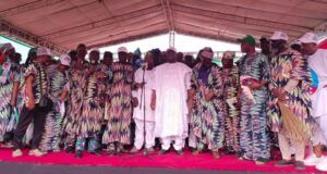 Adelabu Declares Gubernatorial Ambition As Oyo APC Leaders Endorse Him for 2027 Group of people on a stage at a ceremony, many in colorful patterned outfits, with a man in white at center by a microphone.
