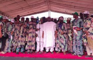 Adelabu Declares Gubernatorial Ambition As Oyo APC Leaders Endorse Him for 2027 Group of people on a stage at a ceremony, many in colorful patterned outfits, with a man in white at center by a microphone.