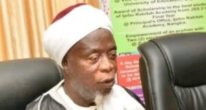 Ijebuland Needs New Awujale Before Sallah, Ijebu Chief Imam Begs Abiodun Religious leader wearing a white turban and robe speaks into a handheld microphone at a conference table.