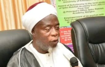 Ijebuland Needs New Awujale Before Sallah, Ijebu Chief Imam Begs Abiodun Religious leader wearing a white turban and robe speaks into a handheld microphone at a conference table.