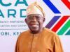 Content Exploitation: Tinubu Hailed By NPO For Directing FCCPC To Investigate Big Tech, AI Platforms Smiling man in tan traditional attire and head wrap posing in front of an Africa-France partnership banner at a formal event
