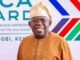 Content Exploitation: Tinubu Hailed By NPO For Directing FCCPC To Investigate Big Tech, AI Platforms Smiling man in tan traditional attire and head wrap posing in front of an Africa-France partnership banner at a formal event