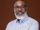 Tinubu Appoints Retired Army General As Special Adviser On Homeland Security Portrait of a mature man with glasses and a gray beard, wearing a blue checkered shirt against a solid brown background.