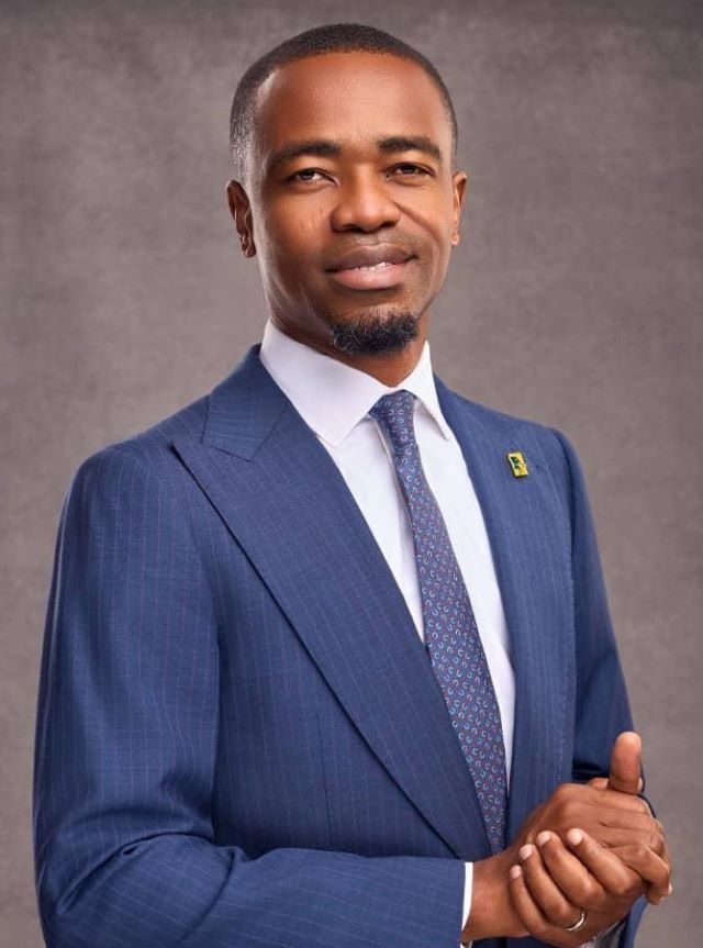 First Bank Professional portrait of a man in a blue pinstripe suit, white shirt, and patterned tie, looking at the camera with a calm smile.
