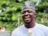 APC Primaries: Abdulganeey Adekunle, ‘Mr. GRA,’Secures House Of Assembly Ticket Smiling man wearing a white traditional outfit with gold trim and a patterned cap outdoors in greenery.