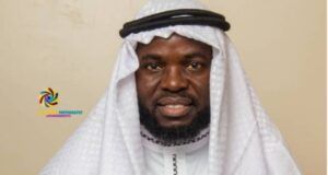 Eid-El-Kabir: Giwa Charges Muslims To Pray For Safe Return Of Abducted Victims In Oyo State Man in white traditional attire with a headscarf, hands held together in front, facing the camera (logo visible on left).