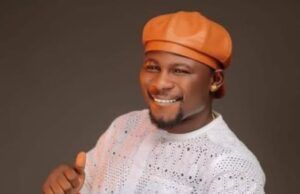 ₦6.56bn Earnings: Kamo State Secures No. 2 Spot In Nollywood Smiling man wearing an orange traditional hat and white lace outfit, giving a thumbs-up gesture toward the camera.