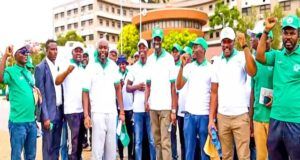 NOA, CIPMN Advocate Mandatory Licensing For Project Management Practice Through Awareness Walk Group of people in green and white shirts standing together outdoors, some raising fists in the air. Crowded in front of a building.