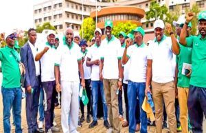 NOA, CIPMN Advocate Mandatory Licensing For Project Management Practice Through Awareness Walk Group of people in green and white shirts standing together outdoors, some raising fists in the air. Crowded in front of a building.