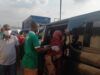 Makinde’s Govt, Security Agencies Clear Ibadan Streets of Destitutes, Beggars A man in a green shirt helps a woman in a red headscarf board a dark bus/van as others wear masks nearby in a busy transport scene.