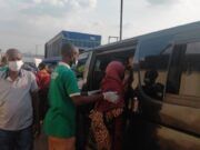 Makinde’s Govt, Security Agencies Clear Ibadan Streets of Destitutes, Beggars A man in a green shirt helps a woman in a red headscarf board a dark bus/van as others wear masks nearby in a busy transport scene.