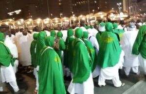 945 Oyo Hajj Pilgrims Arrive In Makkah, As Final Batch Departs for Medina Group of pilgrims in white garments with green shawls walking together at night during a religious procession.