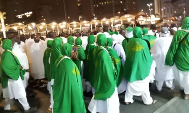 Oyo Pilgrim Group of pilgrims in white garments with green shawls walking together at night during a religious procession.