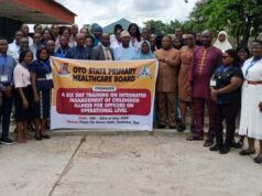 Makinde’s Govt Trains Health Officers On Childhood Illness Management Group of healthcare workers and officials posing outdoors with a banner for an Oyo State health board training event on childhood illness management.