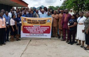 Makinde’s Govt Trains Health Officers On Childhood Illness Management Group of healthcare workers and officials posing outdoors with a banner for an Oyo State health board training event on childhood illness management.