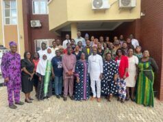 Oyo PHC Board Begins Adaptation of National Safe Pregnancy Termination Guidelines Large diverse group of men and women posing for a group photo outside a brick building with a yellow overhang and air conditioning units above.