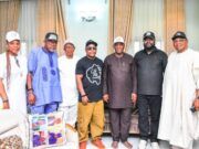 Oyo City Boy Movement Secures Support From Senator Yunus Akintunde Eight people standing together indoors in front of beige curtains, posing for a group photo in varied traditional and casual outfits.