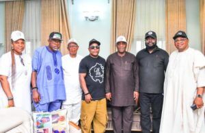 Oyo City Boy Movement Secures Support From Senator Yunus Akintunde Eight people standing together indoors in front of beige curtains, posing for a group photo in varied traditional and casual outfits.