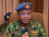Take Fight To Terrorists, Air Staff Chief Tasks Personnel Nigerian Air Force officer in camouflage uniform speaking into a handheld microphone, wearing a blue beret with the force insignia.