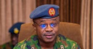 Take Fight To Terrorists, Air Staff Chief Tasks Personnel Nigerian Air Force officer in camouflage uniform speaking into a handheld microphone, wearing a blue beret with the force insignia.