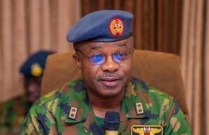 Take Fight To Terrorists, Air Staff Chief Tasks Personnel Nigerian Air Force officer in camouflage uniform speaking into a handheld microphone, wearing a blue beret with the force insignia.