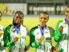 African Senior Athletic Championships: Team Nigeria Wins More Medals Four female athletes in green-and-white jackets hold gold medals, smiling on a track field during an awards ceremony.
