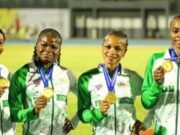 African Senior Athletic Championships: Team Nigeria Wins More Medals Four female athletes in green-and-white jackets hold gold medals, smiling on a track field during an awards ceremony.