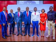 At Pan African Confab, UBA Reaffirms Interest In Deeper Bank-Fintech Collaboration Seven professionals posing on a stage for a conference photo, dressed in suits and a red dress.