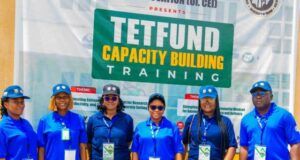 ‘Universities Judged By Research Relevance, Impact, Not Infrastructure’ Group of seven people in blue uniforms posing in front of a banner that says 'TETFUND Capacity Building Training' at a training event.