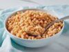 Nutritionists’ Pronouncement: Beans Contain More Carbohydrates Than Protein White bowl filled with cooked chickpeas and a metal spoon resting in them on a light blue cloth